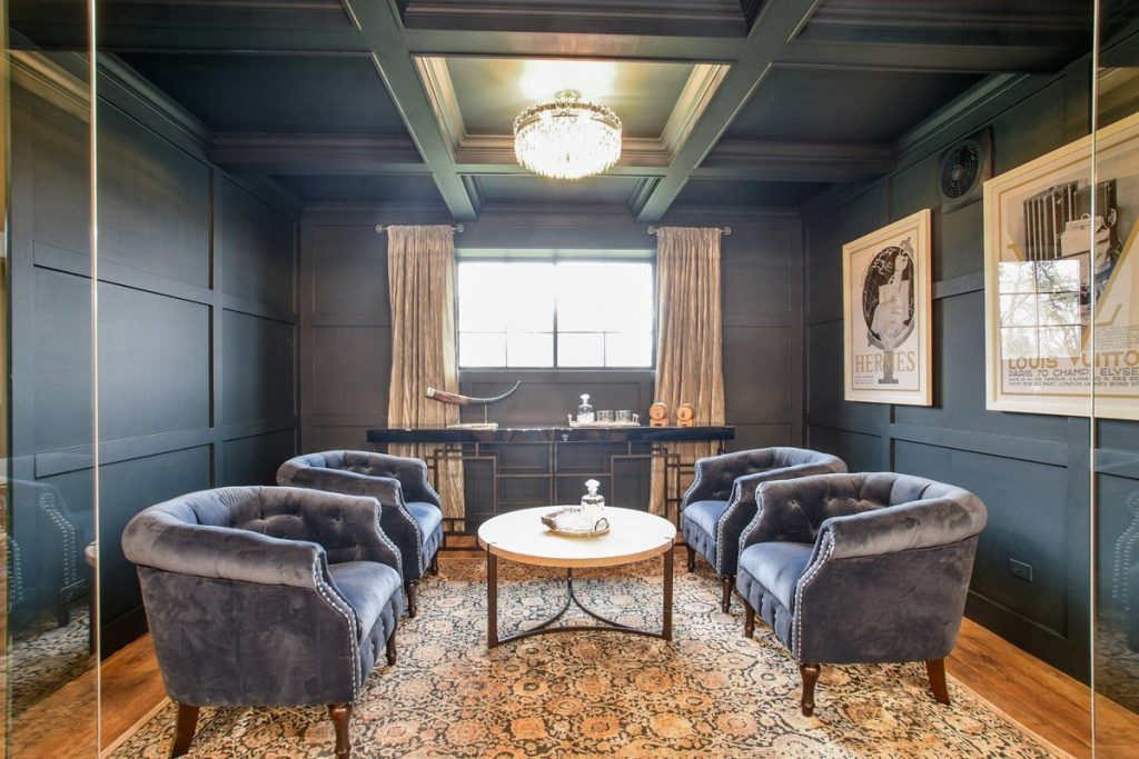 Lounge with 4 blue chairs and dark blue walls with matching molding.